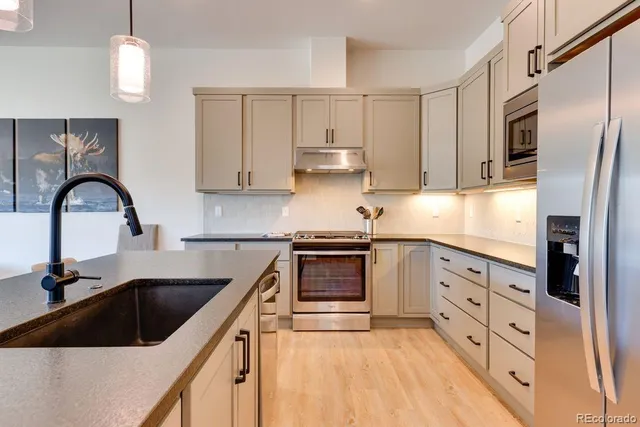 a kitchen with granite countertop a sink a stove and refrigerator