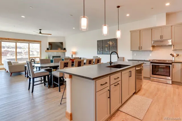 a kitchen with stainless steel appliances granite countertop a stove a sink a microwave a dining table and chairs with wooden floor