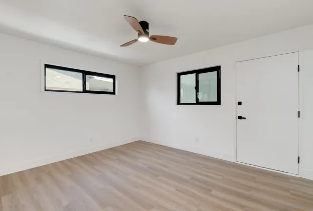 a view of an empty room with a window and wooden floor