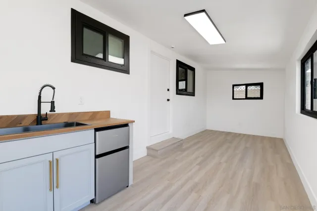 an empty room with wooden floor chandelier fan and windows
