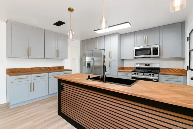 a kitchen with stainless steel appliances a stove a sink a microwave a refrigerator and cabinets