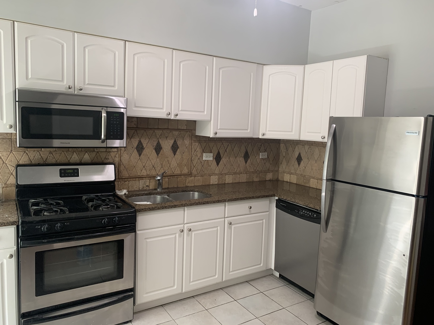Undisclosed Address Chicago, IL 60613 - Photo 2 of 22 a kitchen with white cabinets and stainless steel appliances