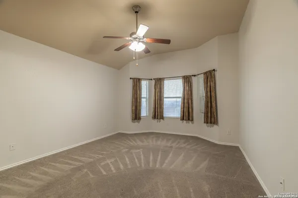 a view of an empty room with chandelier fan and a window