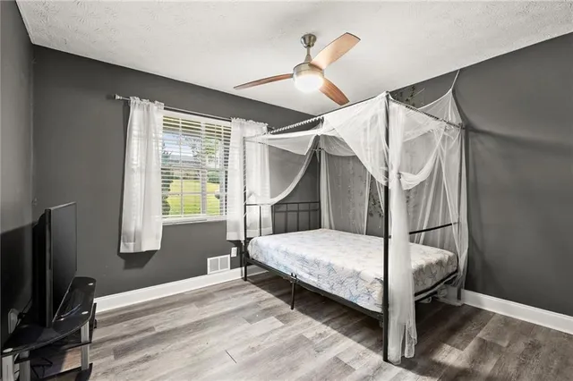 a bedroom with a bed a window and a flat screen tv