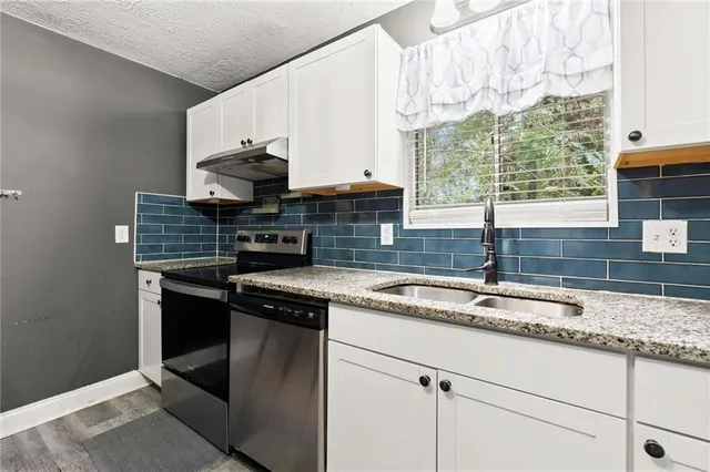 a kitchen with stainless steel appliances granite countertop a sink stove and cabinets