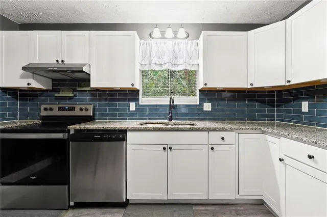 a kitchen with granite countertop a sink stainless steel appliances and cabinets