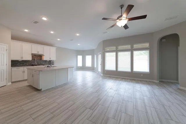 a view of an empty room with wooden floor and a kitchen