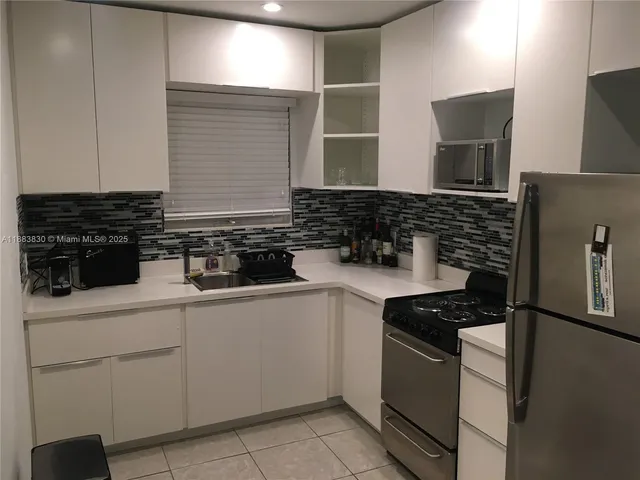 a kitchen with white cabinets and appliances