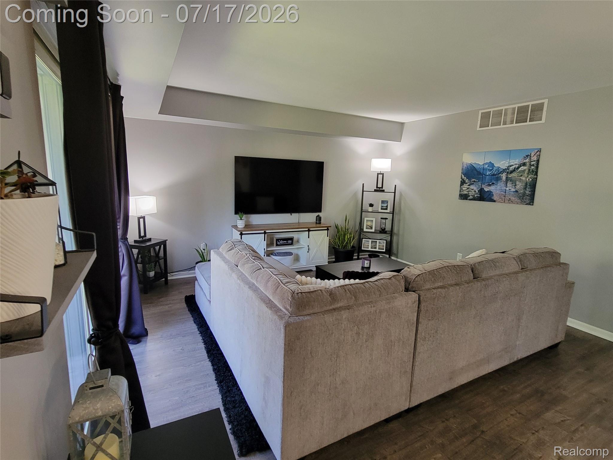 1655 Riverside Drive, Unit 10 Rochester, MI 48309 - Photo 19 of 44 Spacious living area featuring wood-finish flooring, neutral wall tones, and a tray ceiling