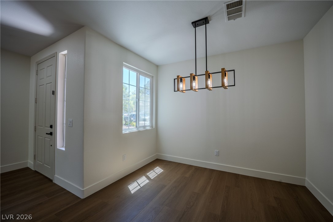 1832 Spring Summit Lane Las Vegas, NV 89134 - Photo 9 of 52 A contemporary chandelier illuminates this versatile space, featuring rich wood flooring and a bright window.