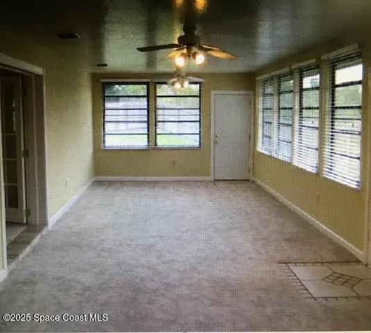 en empty room with windows and chandelier fan