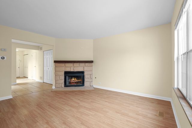 an empty room with wooden floor fireplace and windows