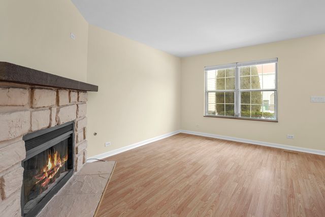 a view of an empty room with wooden floor fireplace and a window