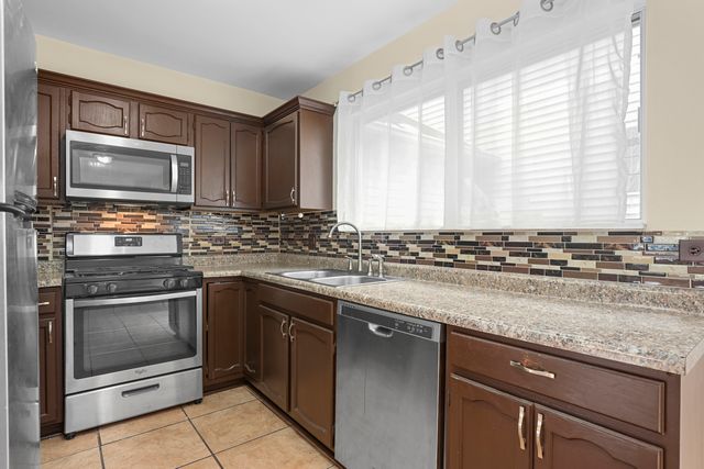 a kitchen with granite countertop a stove sink and microwave