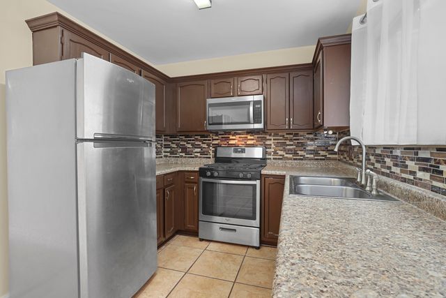 a kitchen with granite countertop a refrigerator and a stove top oven