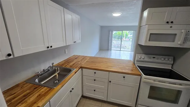 a kitchen with granite countertop white cabinets and white appliances