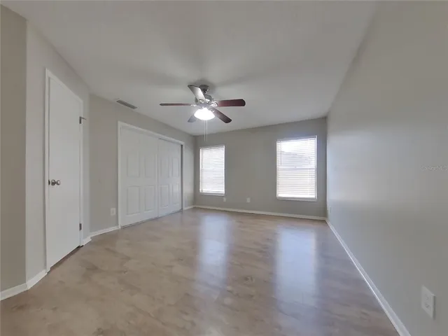 a view of an empty room with window and wooden floor