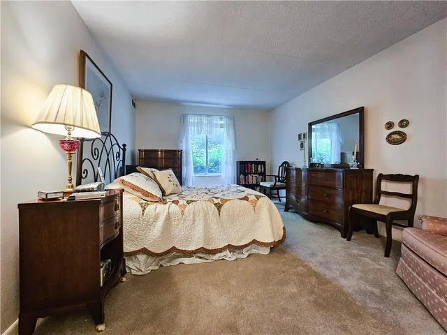 a spacious bedroom with a bed large window and dresser
