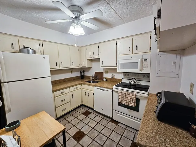 a kitchen with cabinets a sink and white appliances