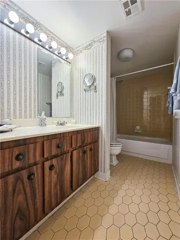a bathroom with a double vanity sink a toilet a mirror and shower