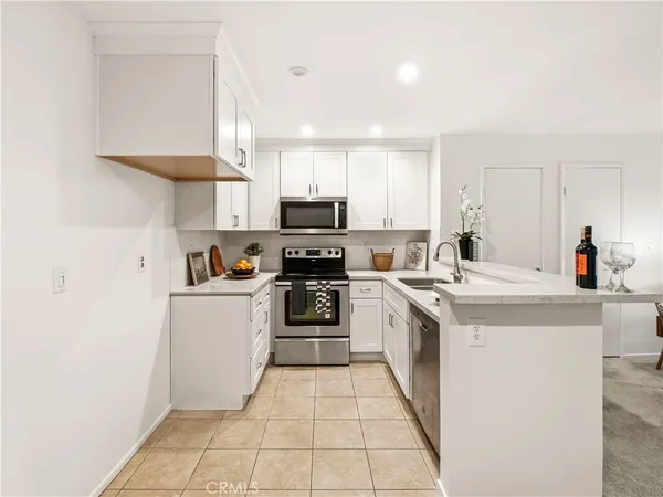 a kitchen with a sink a stove top oven and white cabinets