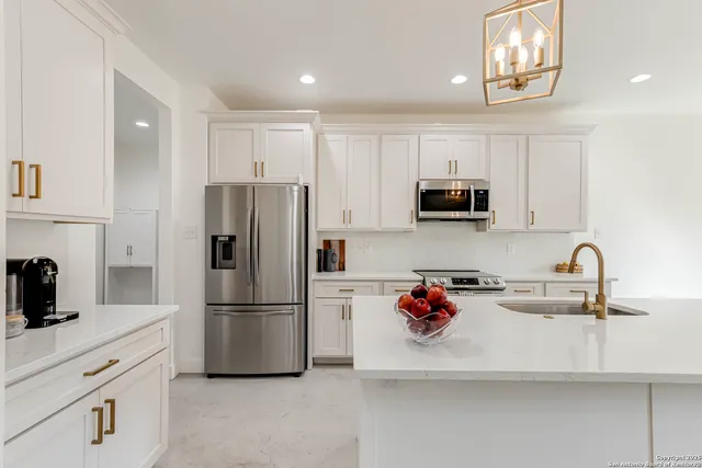 a kitchen with refrigerator a microwave a sink and cabinets