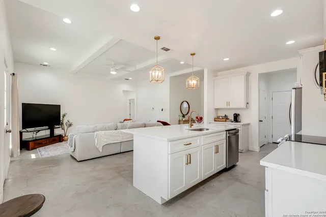a large white kitchen with a sink and a stove top oven
