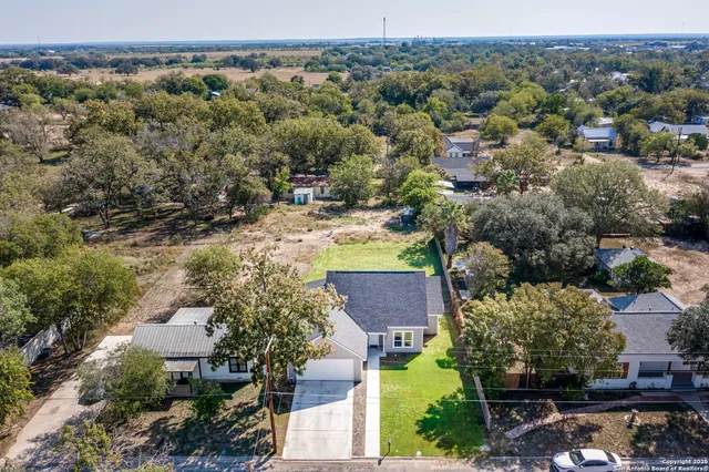 an aerial view of residential houses with outdoor space and trees