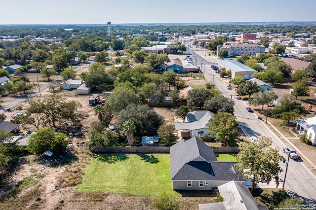 an aerial view of residential houses with outdoor space and trees