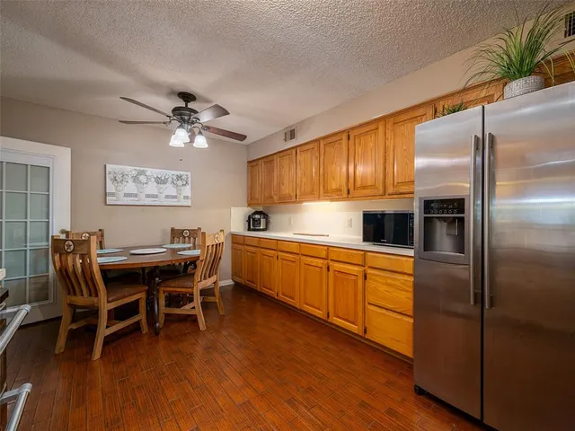 a kitchen with stainless steel appliances granite countertop a dining table chairs and wooden floor