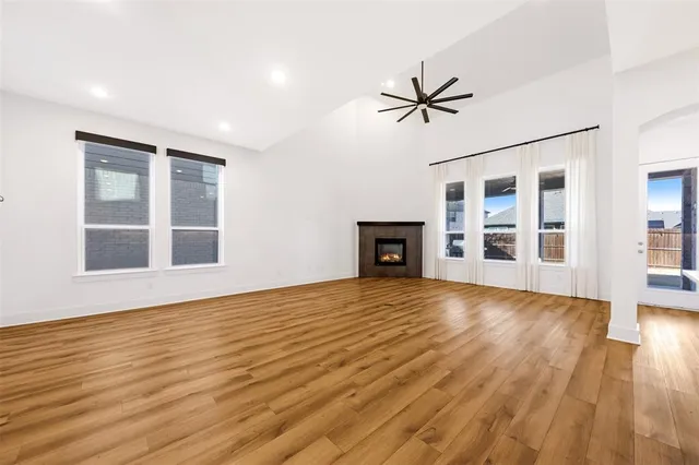 a view of empty room with wooden floor and fan