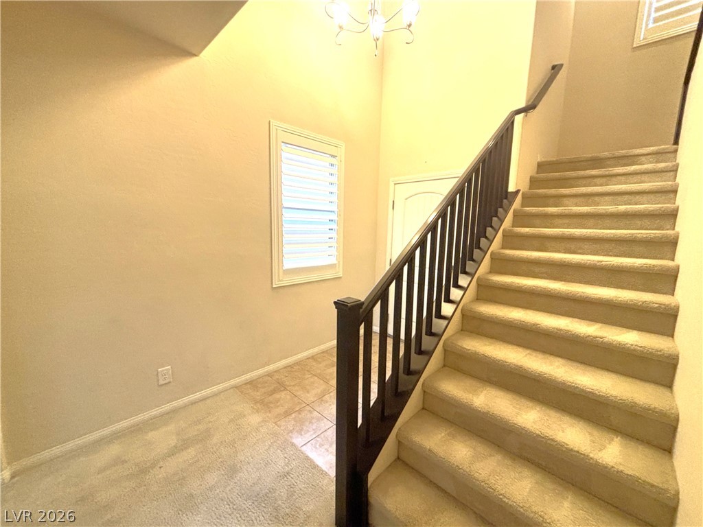 121 Elm Reed Avenue Las Vegas, NV 89113 - Photo 6 of 30 Ascend to the upper level on a plush carpeted staircase, bathed in light from an elegant window.
