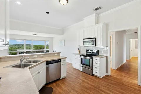 a kitchen with stainless steel appliances granite countertop a sink a stove and a refrigerator