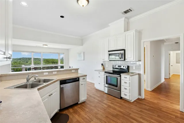 a kitchen with stainless steel appliances granite countertop a sink a stove and a refrigerator