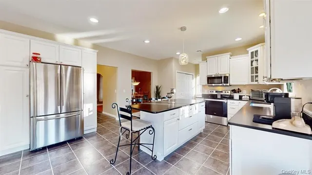 a kitchen with stainless steel appliances kitchen island granite countertop a refrigerator a stove a sink and a refrigerator