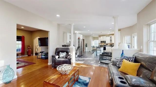 a living room with furniture kitchen view and a wooden floor