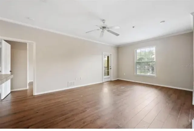 a view of an empty room with wooden floor and a window