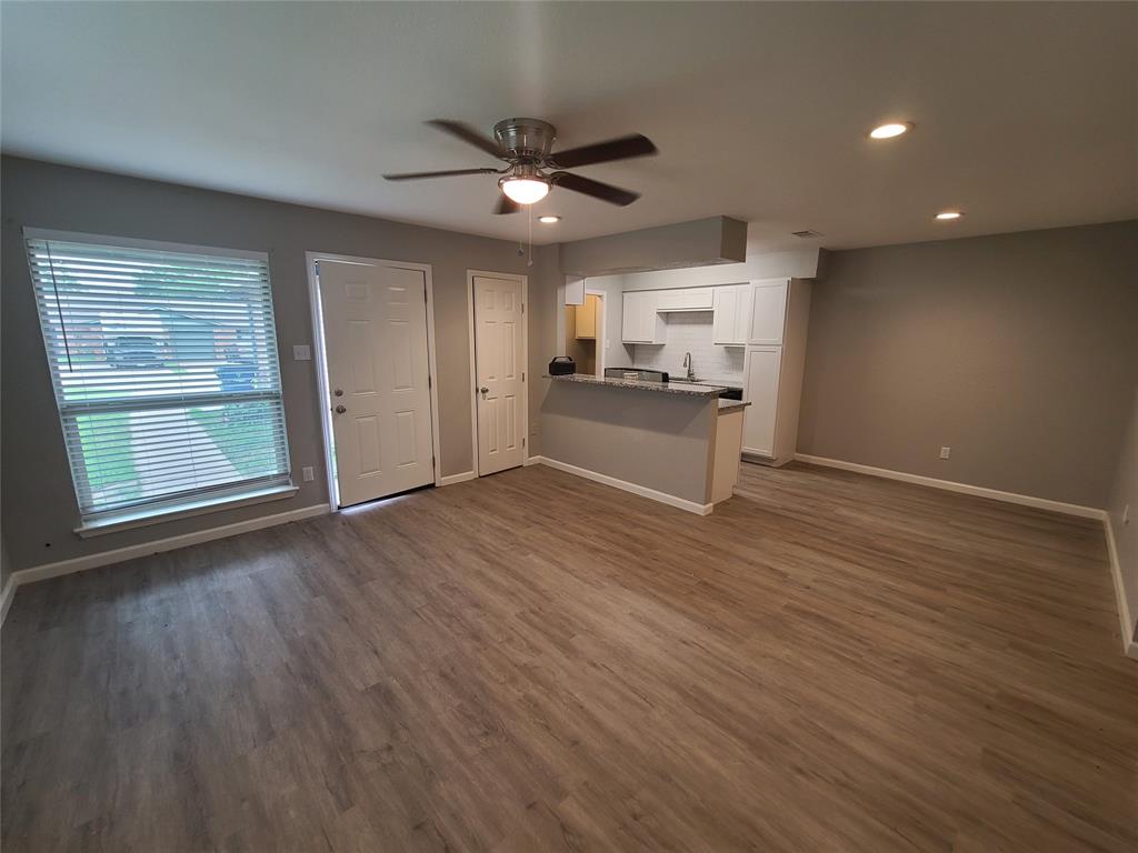 a view of a kitchen with wooden floor a sink a refrigerator and window