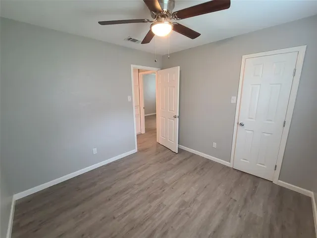 an empty room with wooden floor a ceiling fan and closet