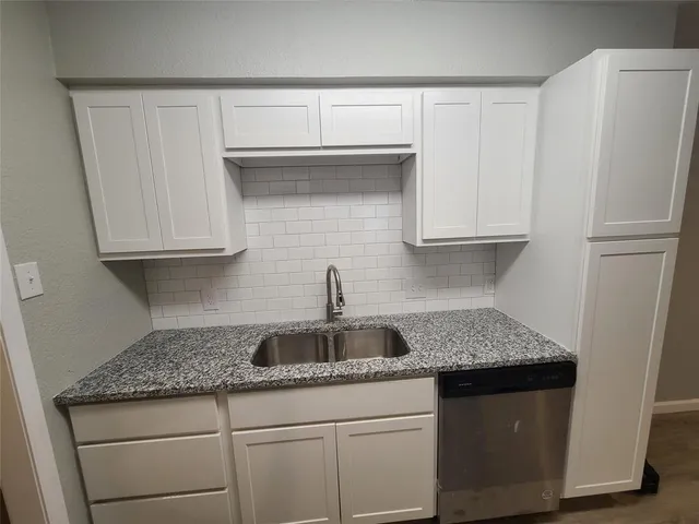 a kitchen with granite countertop white cabinets and refrigerator
