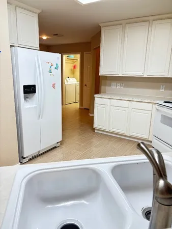 a kitchen with a refrigerator and white cabinets