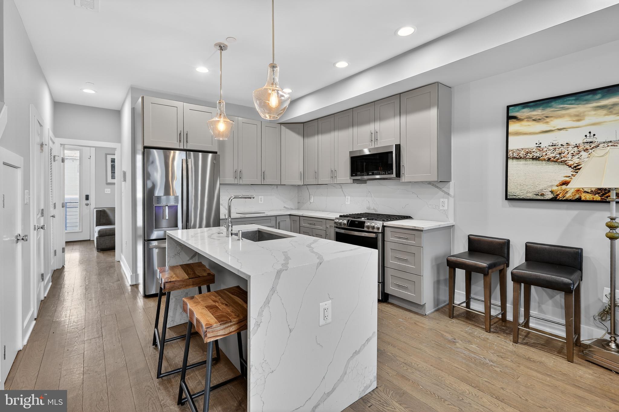 a kitchen with a refrigerator a stove a microwave a dining table and chairs with wooden floor