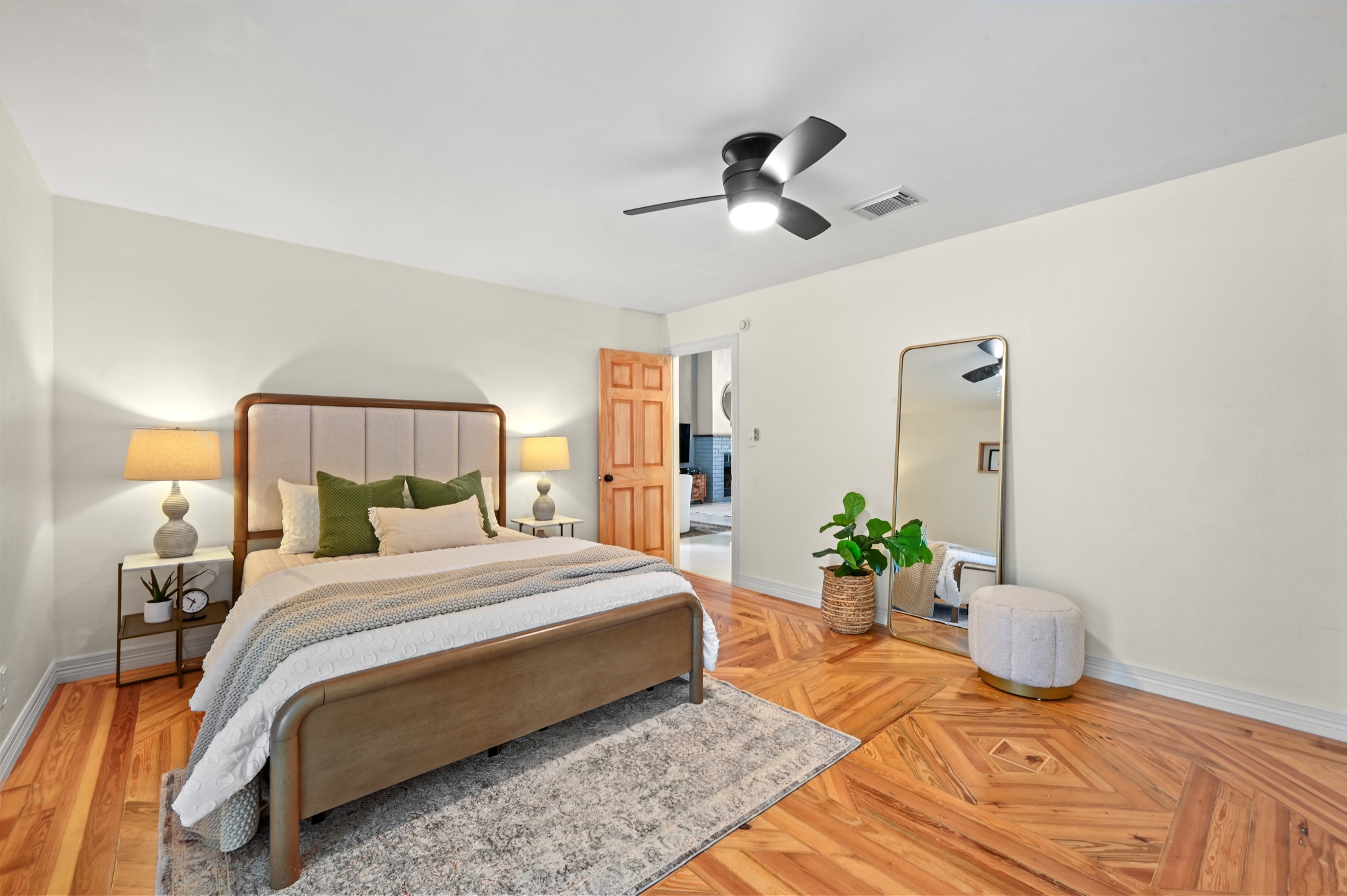 708 Shade Tree Drive Austin, TX 78748 - Photo 16 of 32 The main floor primary suite is a secluded retreat with beautiful custom, reclaimed wood floors and a stylish modern fan.