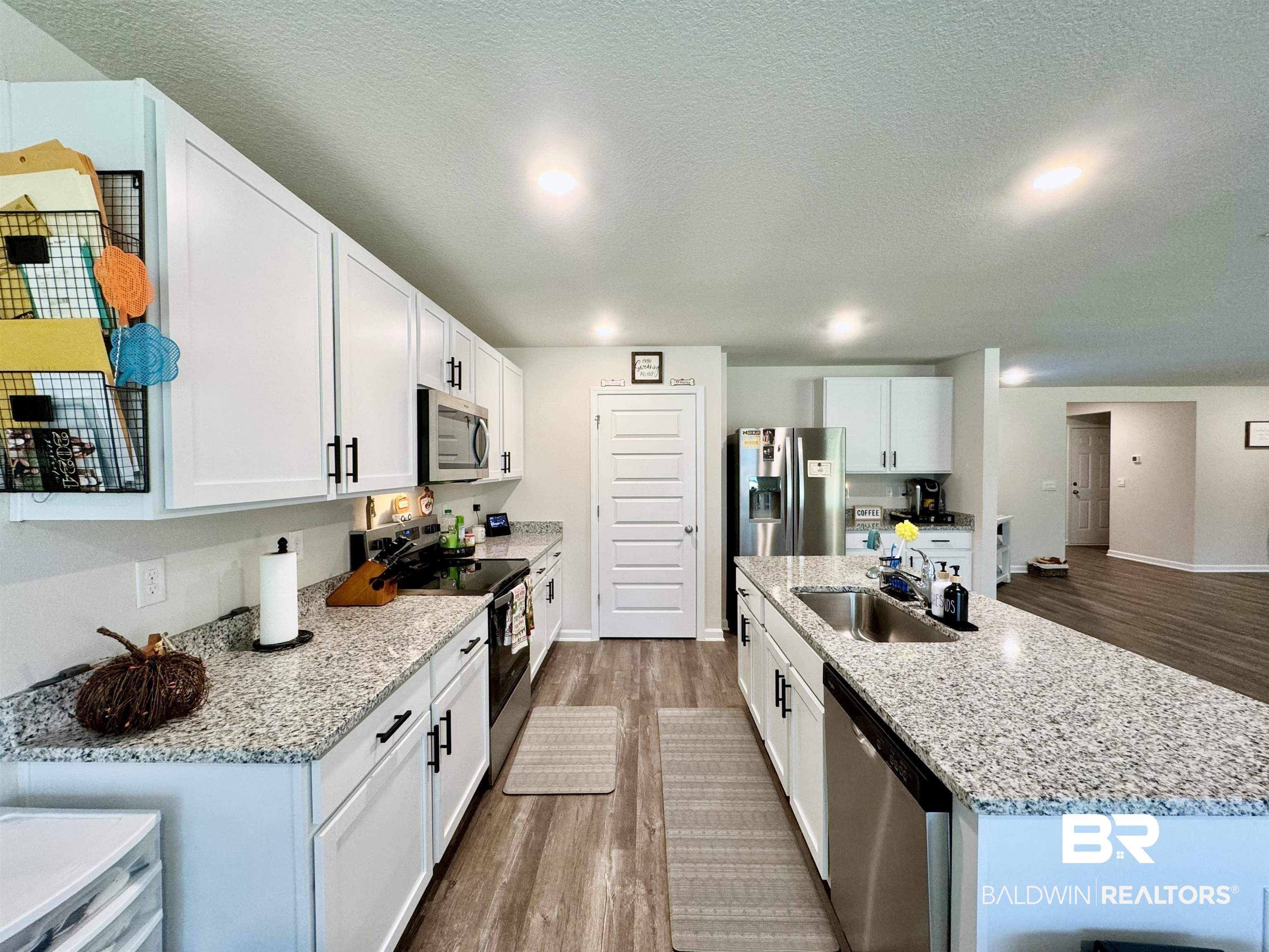 24216 Ringneck Loop Elberta, AL 36530 - Photo 8 of 23 Kitchen featuring stainless steel appliances, light wood-style flooring, white cabinetry, a kitchen island with sink, and a textured ceiling