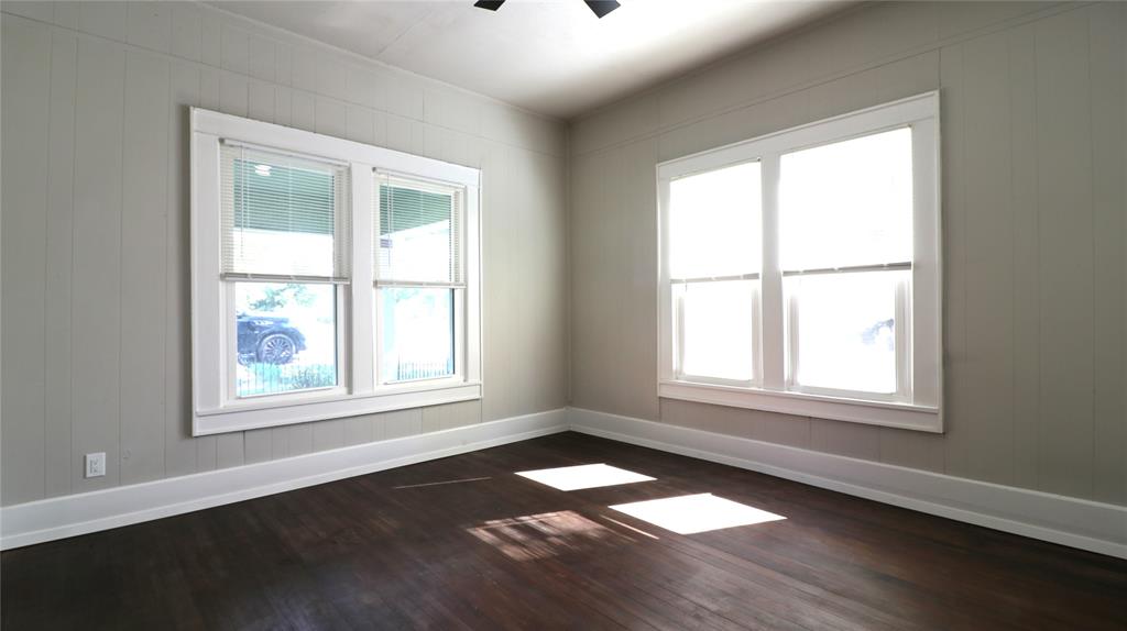 929 Vitalious Street Ranger, TX 76470 - Photo 11 of 22 Spare room with dark wood-style floors, healthy amount of natural light, wooden walls, and ceiling fan