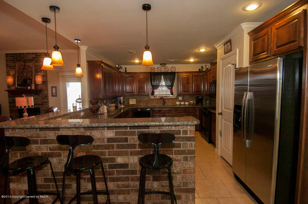 18301 Copper Ridge Bushland, TX 79124 - Photo 6 of 38 a kitchen with kitchen island granite countertop a refrigerator a stove a sink and a dining table with wooden floor