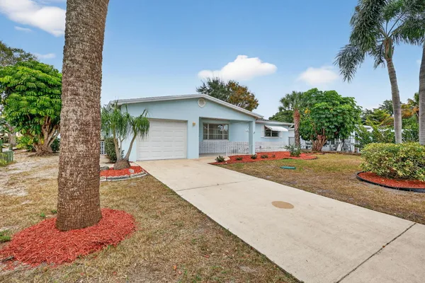 a front view of a house with a yard and potted plants