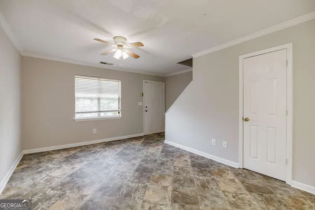 an empty room with wooden floor fan and windows