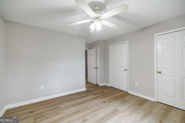 an empty room with wooden floor fan and windows