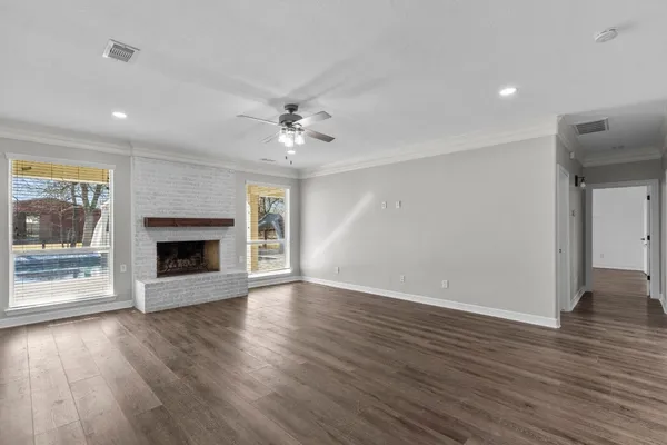 a view of an empty room with window and wooden floor